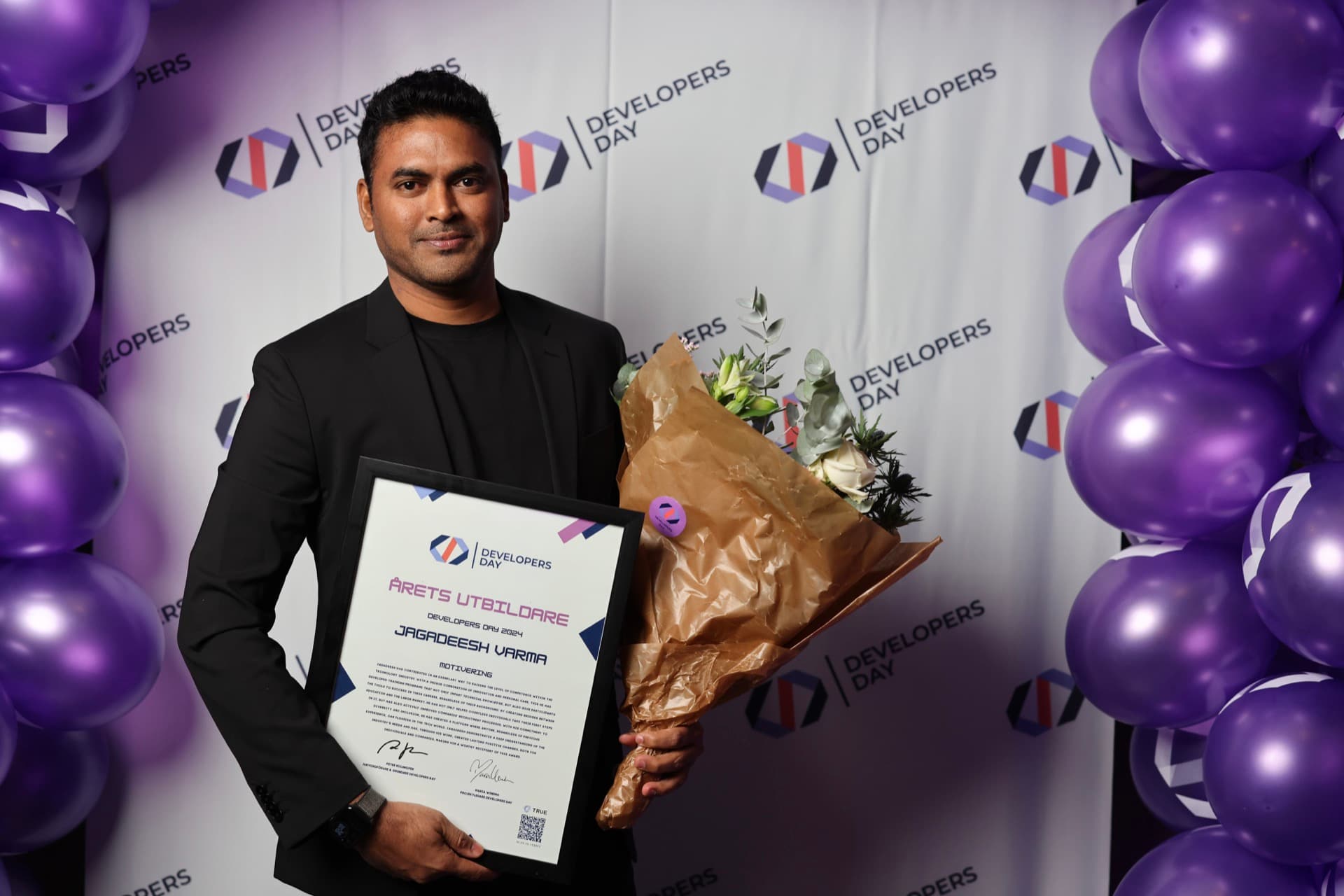 Jagadeesh Varma holding his Educator of the Year certificate and a bouquet